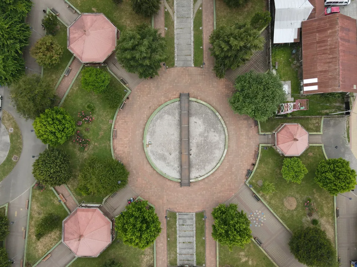 Top-down view of a circular plaza with pathways and greenery in a city park.